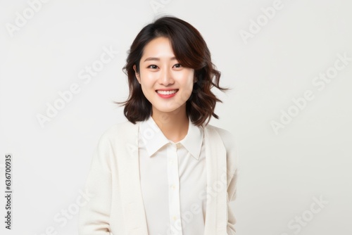 Medium shot portrait of a Chinese woman in her 20s in a white background wearing a chic cardigan