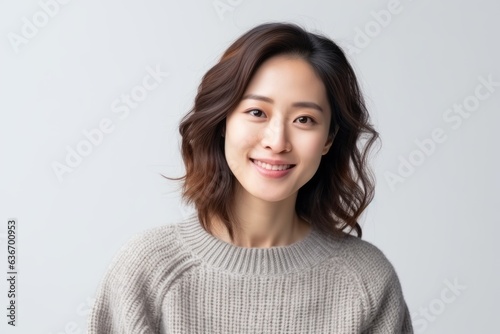 Medium shot portrait of a Chinese woman in her 30s in a white background wearing a cozy sweater