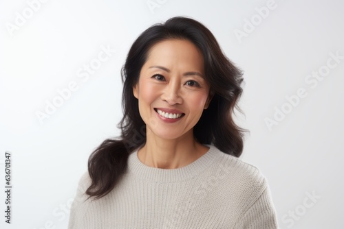 Medium shot portrait of a Chinese woman in her 40s in a white background wearing a cozy sweater © Anne-Marie Albrecht