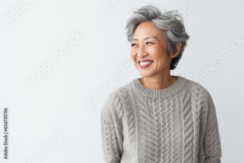 Lifestyle portrait of a Chinese woman in her 50s in a white background wearing a cozy sweater