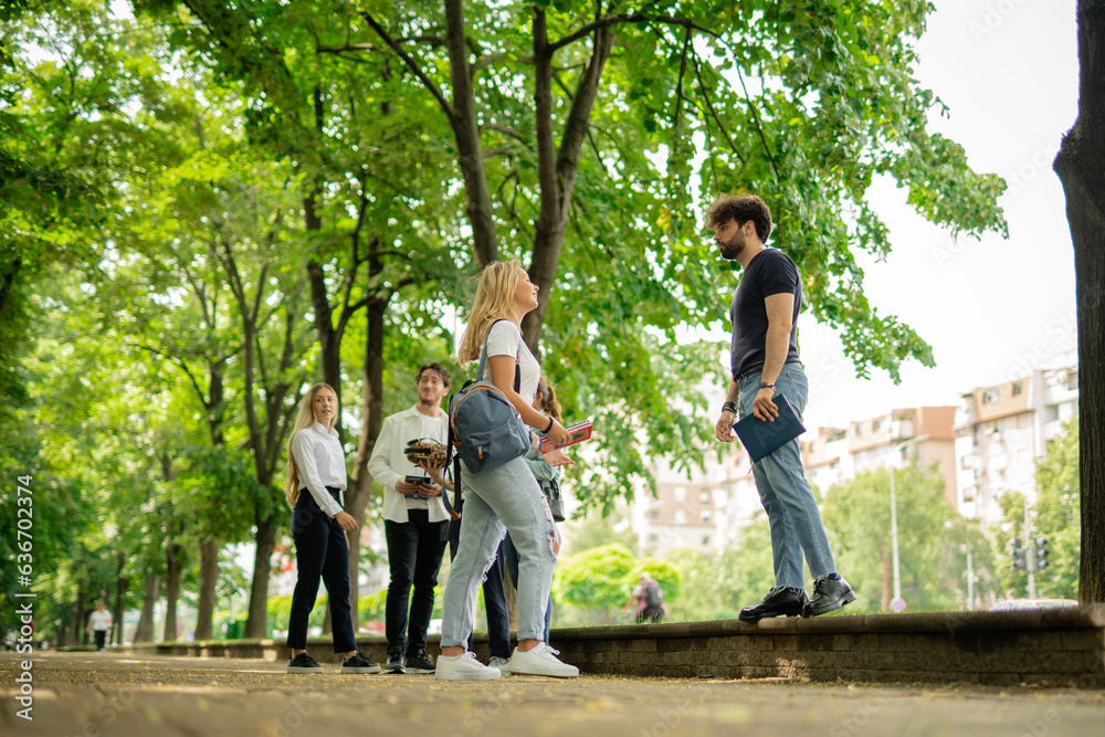 Obraz premium Happy students having a conversation while standing on a sidewalk in front of the university