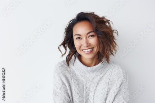 Lifestyle portrait of a Indonesian woman in her 30s in a white background wearing a cozy sweater © Anne-Marie Albrecht