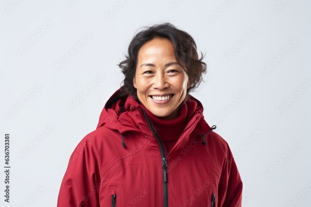 Medium shot portrait of a Indonesian woman in her 50s in a white background wearing a warm parka Medium shot portrait of a Indonesian woman in her 50s in a white background wearing a warm parka