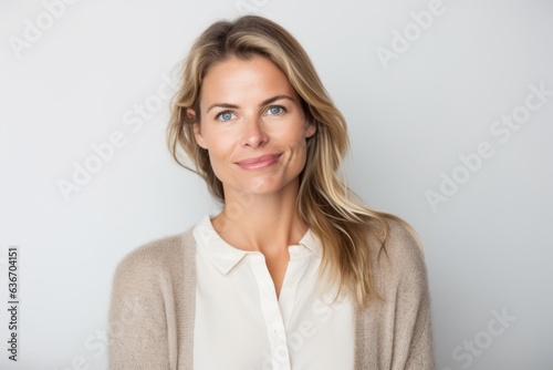 Close-up portrait of a Russian woman in her 30s in a white background wearing a chic cardigan
