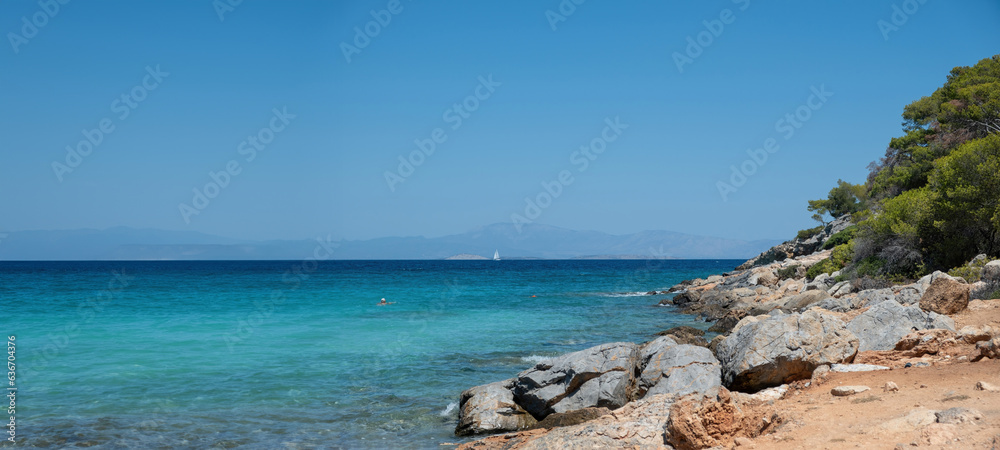 Agistri Island Greece. Rocky beach, landscape covered with pine tree, crystal sea, blue sky. Banner