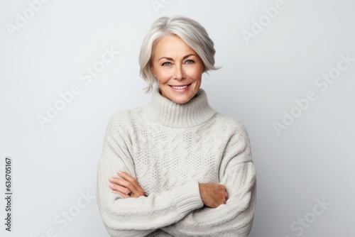 Medium shot portrait of a Russian woman in her 60s in a white background wearing a cozy sweater