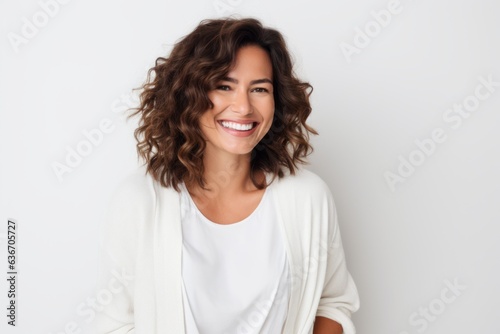 Lifestyle portrait of a Brazilian woman in her 30s in a white background wearing a chic cardigan