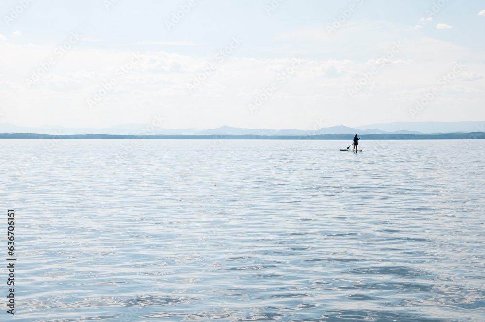 Seascape of Uvildy lake in summer with a silhouette of a supboarder, South Urals, Russia
