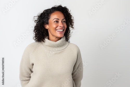 Lifestyle portrait of a Brazilian woman in her 40s in a white background wearing a cozy sweater