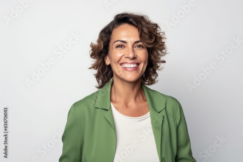 Medium shot portrait of a Brazilian woman in her 40s in a white background wearing a chic cardigan © Anne-Marie Albrecht