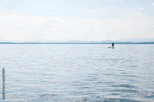 Seascape of Uvildy lake in summer with a silhouette of a supboarder, South Urals, Russia photo