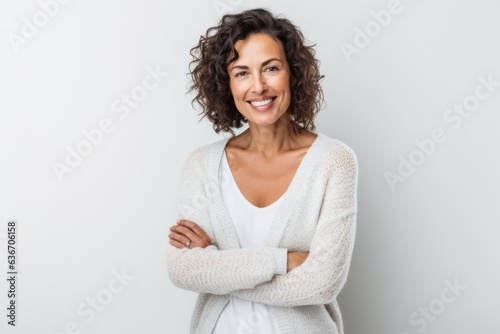 Lifestyle portrait of a Brazilian woman in her 40s in a white background wearing a chic cardigan
