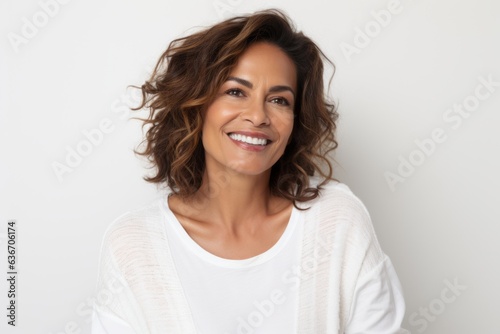 Lifestyle portrait of a Brazilian woman in her 40s in a white background wearing a chic cardigan