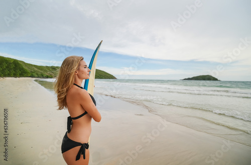 Mature woman carries surfboard into gentle waves