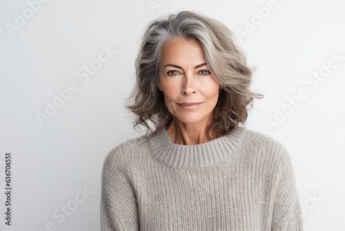 Lifestyle portrait of a Brazilian woman in her 50s in a white background wearing a cozy sweater