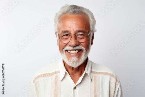 Medium shot portrait of a Brazilian man in his 80s in a white background wearing a chic cardigan