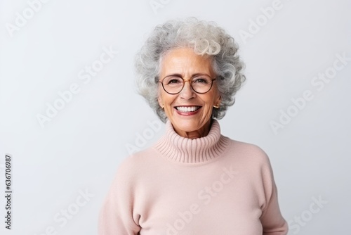 Medium shot portrait of a Brazilian woman in her 90s in a white background wearing a cozy sweater