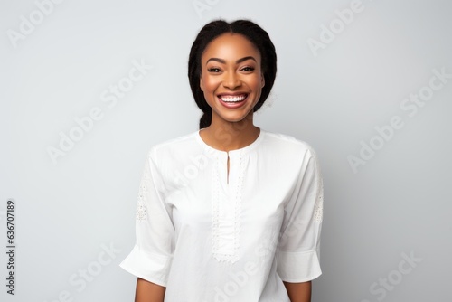Lifestyle portrait of a Nigerian woman in her 20s in a white background wearing a simple tunic