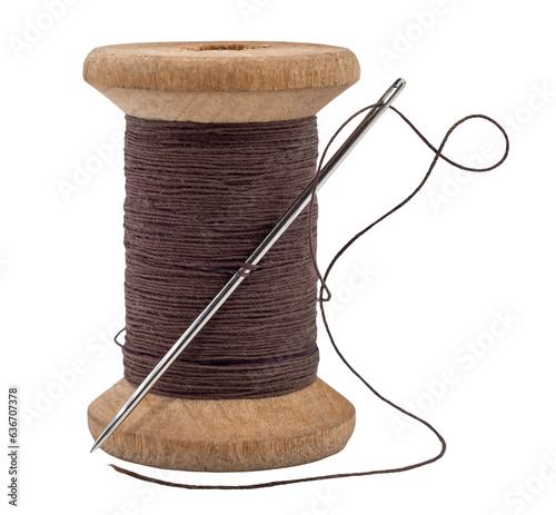 Old wooden spool of thread and needle on a white background. Sewing accessories