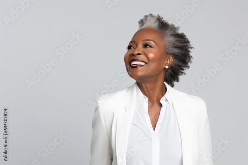 Lifestyle portrait of a Nigerian woman in her 50s in a white background wearing a classic blazer