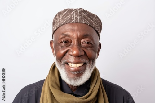 Medium shot portrait of a Nigerian man in his 70s in a white background wearing a charming scarf