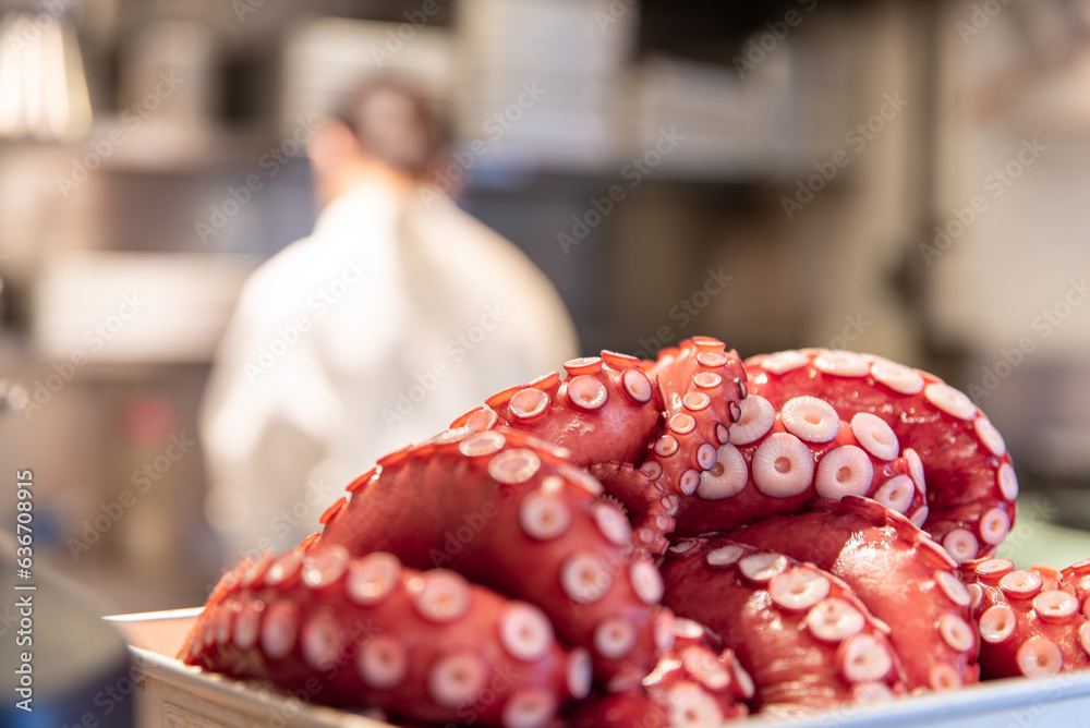Octopus tentacles in a japanese restaurant kitchen, with a japanese chef in the background