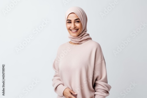 Portrait of a happy muslim woman in hijab standing isolated over white background