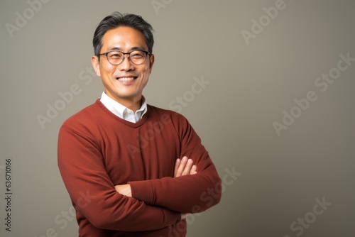 Portrait of mature Asian man wearing eyeglasses against gray background