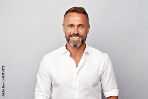 smiling handsome man in white shirt looking at camera on grey background