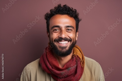 Portrait of a happy young bearded Indian man wearing scarf and looking at camera