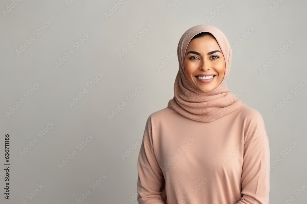 Portrait of happy muslim woman in hijab looking at camera over grey background Portrait of happy muslim woman in hijab looking at camera over grey background