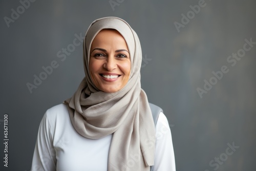 portrait of smiling muslim woman in hijab looking at camera over grey background