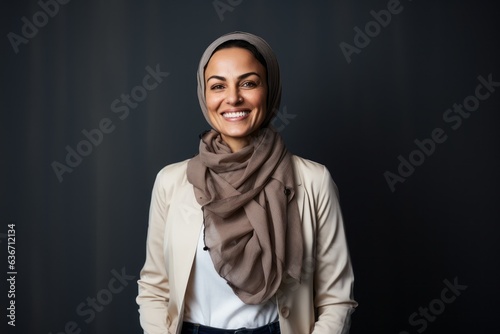 Portrait of a smiling muslim woman wearing hijab over grey background