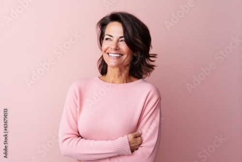 Medium shot portrait of a Brazilian woman in her 50s in a pastel or soft colors background wearing a cozy sweater