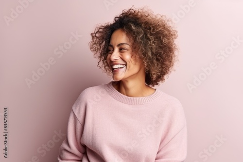 Medium shot portrait of a Brazilian woman in her 50s in a pastel or soft colors background wearing a cozy sweater