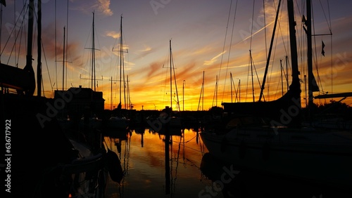Fototapeta Naklejka Na Ścianę i Meble -  
Sunset in the harbor with sailboats and motorboats a setting sun in the evening, the golden hour that is also at morning, rising sun.
