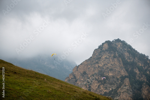 Beautiful mountain landscape with rocks, fog and paragliders