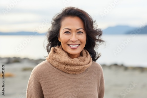 Lifestyle portrait of a Indonesian woman in her 40s in a beach background wearing a cozy sweater © Leon Waltz