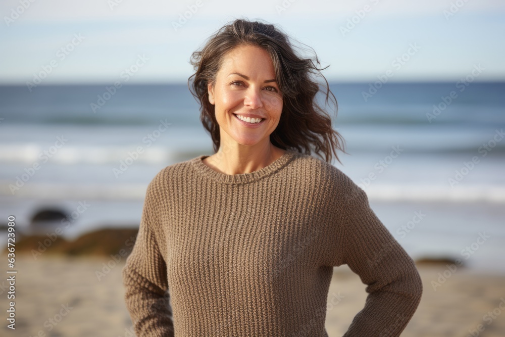 Medium shot portrait of a Russian woman in her 40s in a beach background wearing a cozy sweater Medium shot portrait of a Russian woman in her 40s in a beach background wearing a cozy sweater