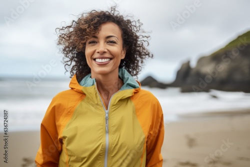 Lifestyle portrait of a Brazilian woman in her 40s in a beach background wearing a lightweight windbreaker