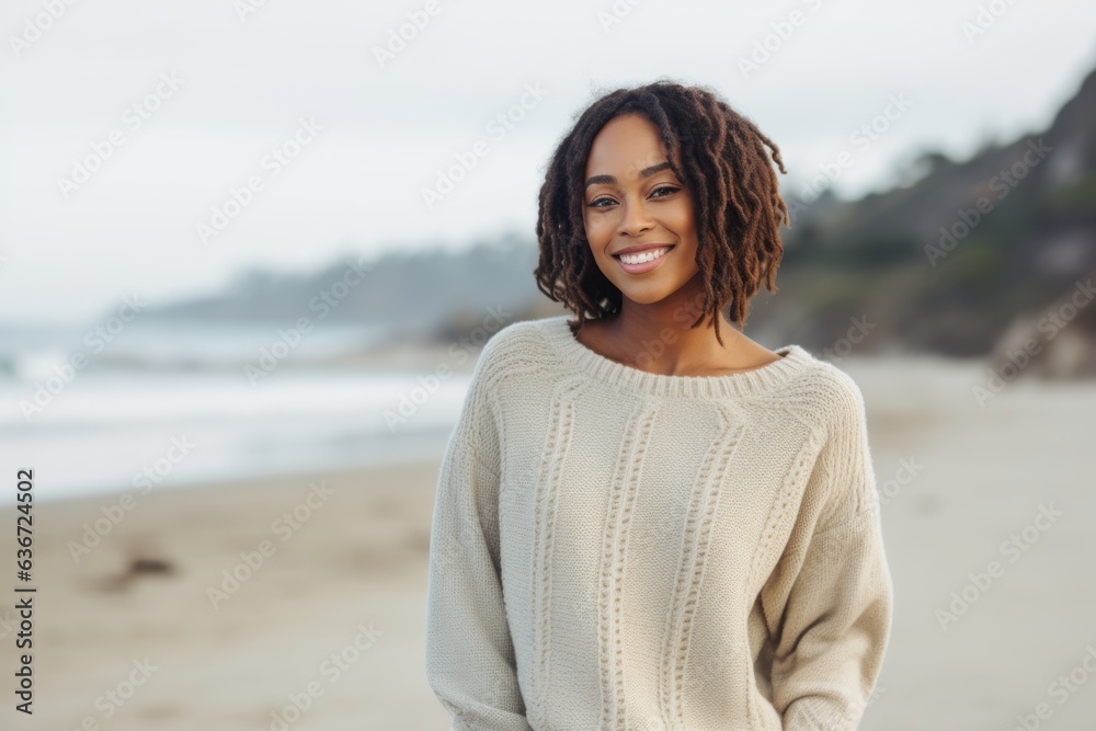 Lifestyle portrait of a Nigerian woman in her 20s in a beach background wearing a cozy sweater Lifestyle portrait of a Nigerian woman in her 20s in a beach background wearing a cozy sweater