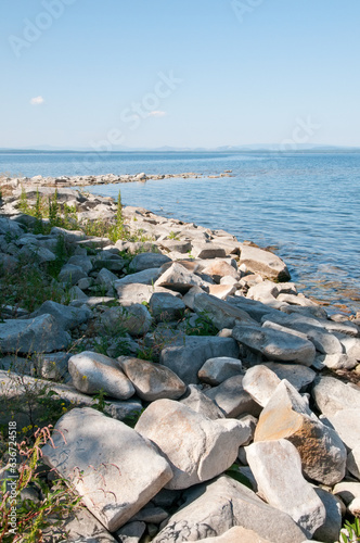 Coastline of lake Uvildy in summer with boulders in the foreground, South Urals, Russian Federation photo