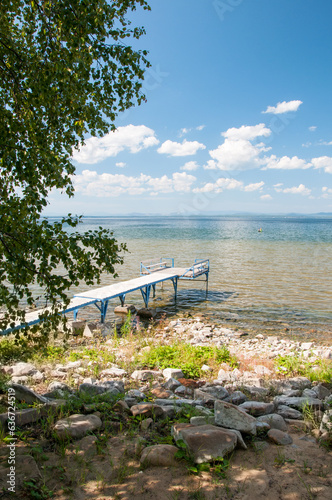 Lake Uvildy in summer with a pier on its rocky shore, South Urals, Russian Federation photo