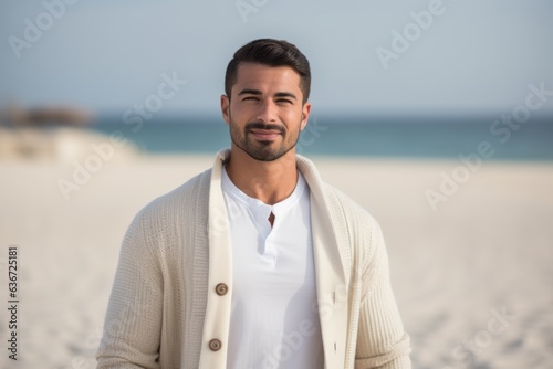 Portrait of handsome young man standing on the beach and looking at camera