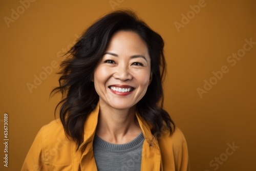 Portrait of a smiling asian woman looking at camera over yellow background