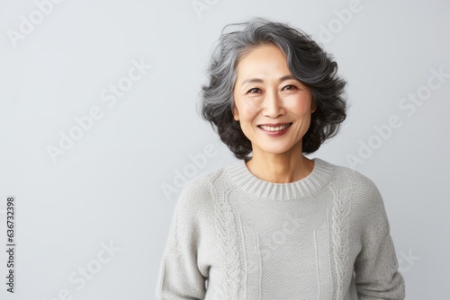 Portrait of smiling senior asian woman with gray hair and grey sweater.
