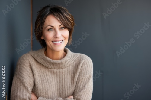 Portrait of a smiling businesswoman standing with arms crossed against grey background