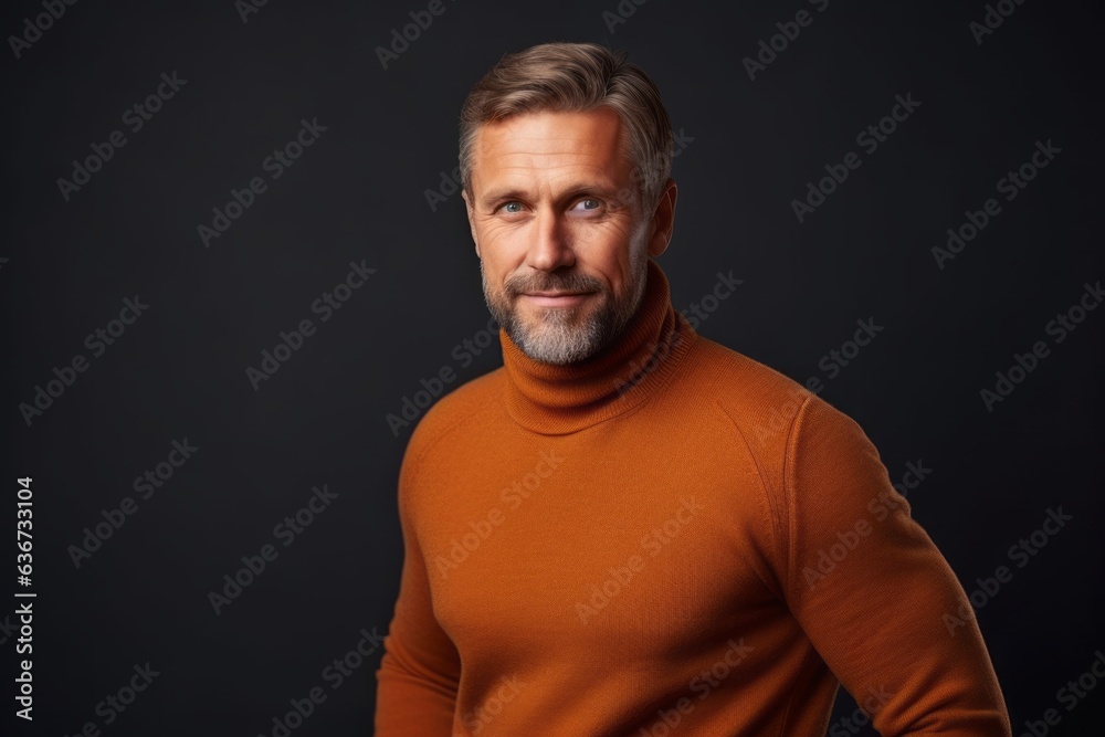 Portrait of handsome mature man in orange sweater on black background.