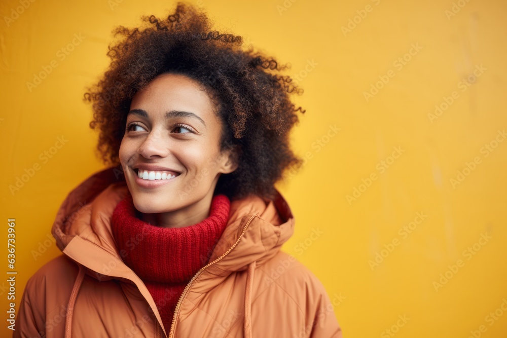 Portrait of a smiling young african american woman in winter clothes standing against yellow background Portrait of a smiling young african american woman in winter clothes standing against yellow background