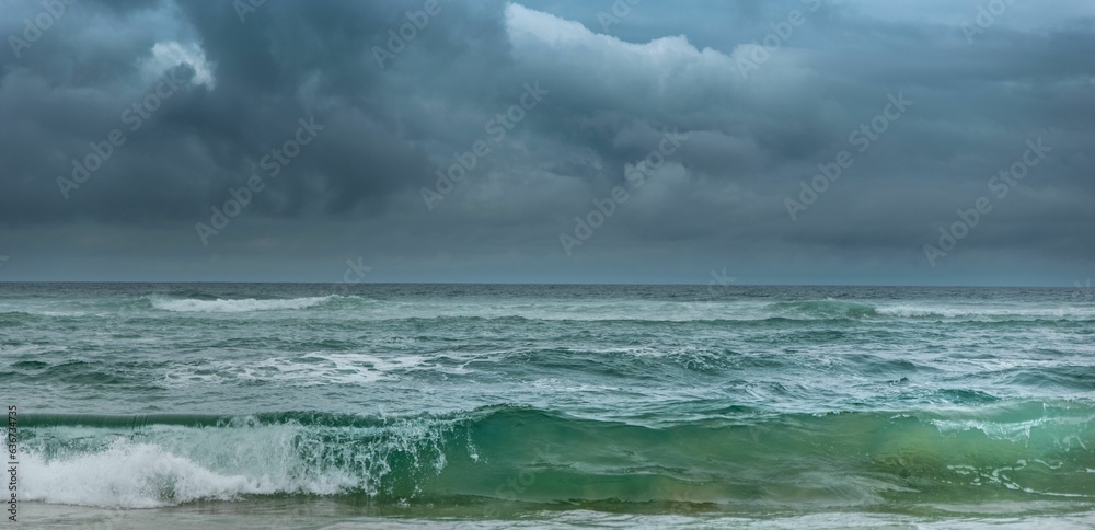 Green wave breaking under dark cloudy skies with a storm approaching Green wave breaking under dark cloudy skies with a storm approaching